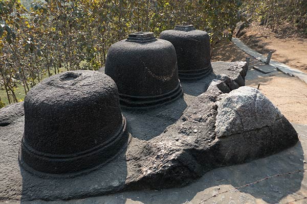 Three Buddhist votive stupas carved from single boulder